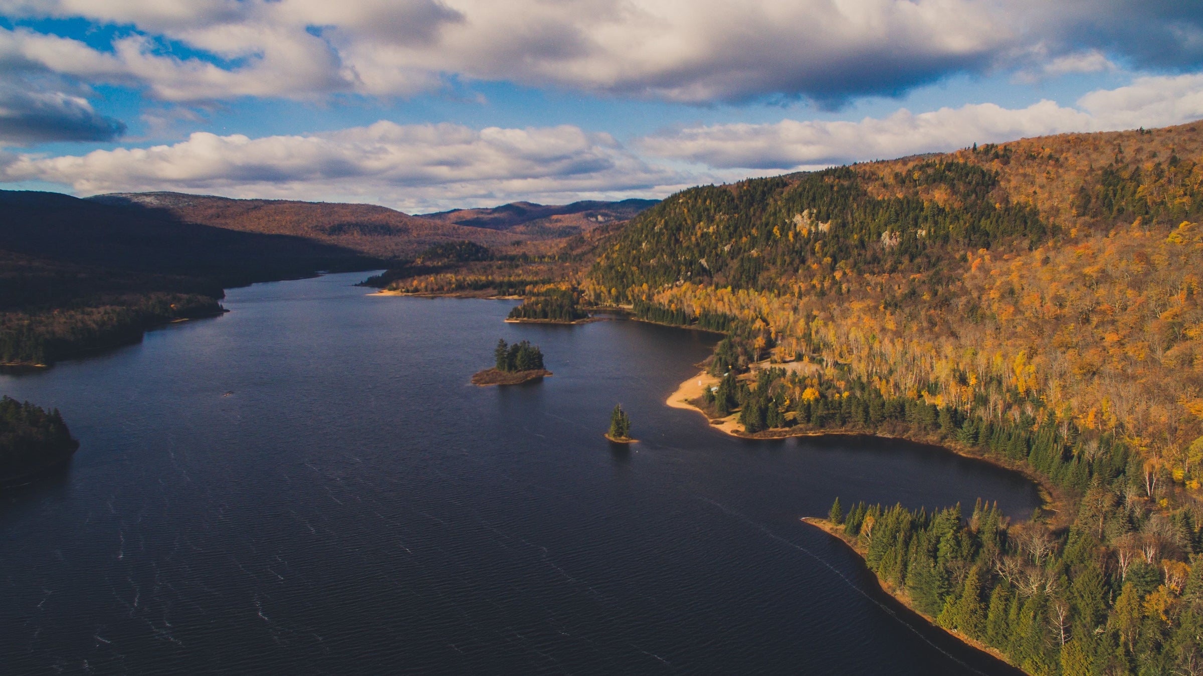 image of lake and hills covered by trees with autumn colored leaves