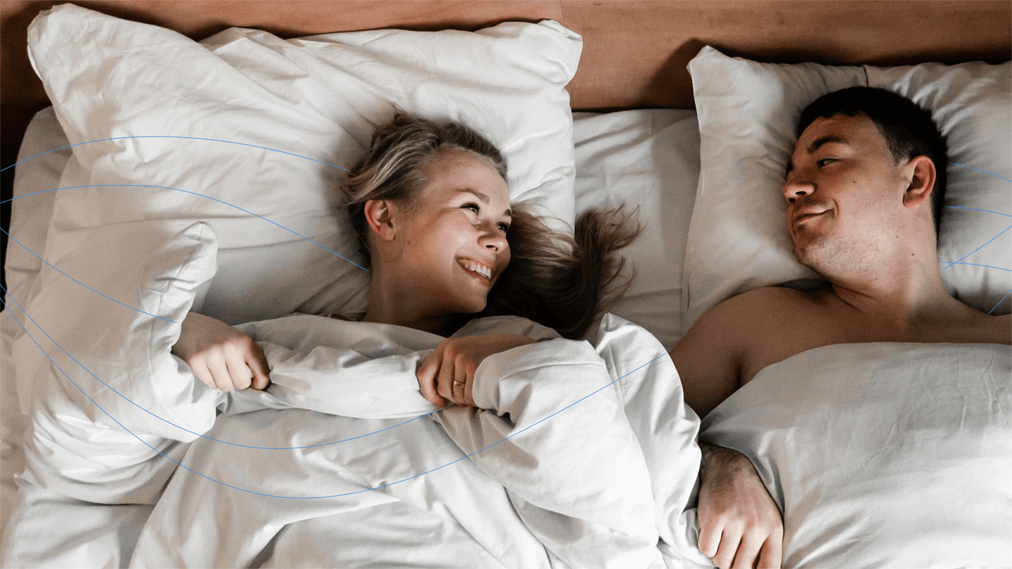 happy customers: a smiling man and woman looking at each other while lying on the bed