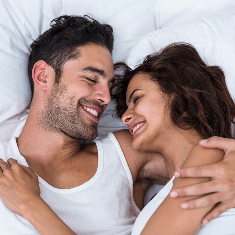 happy customers. a smiling man and woman looking at each other while lying on the bed