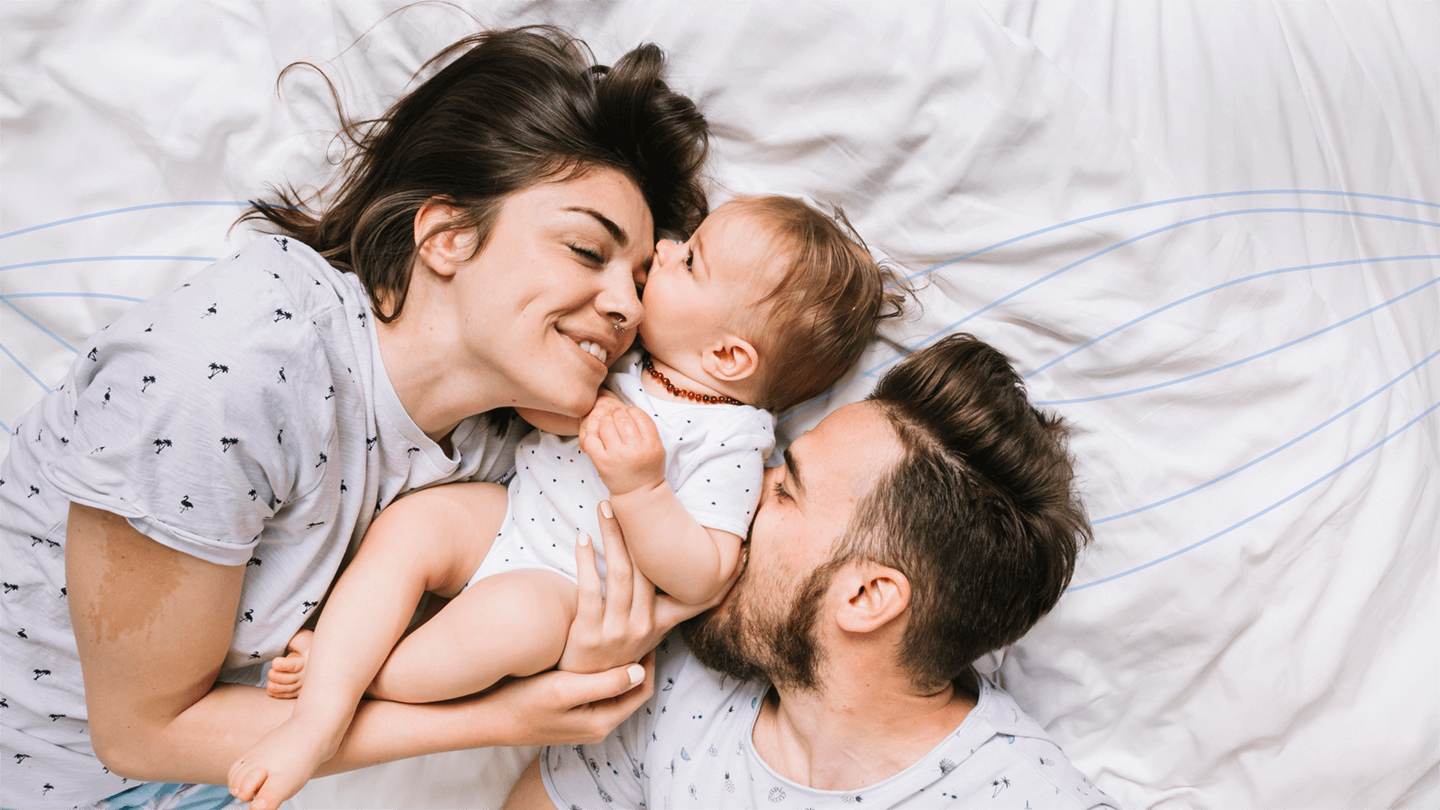 happy customers. a man and smiling woman playing with their small baby while lying on the bed